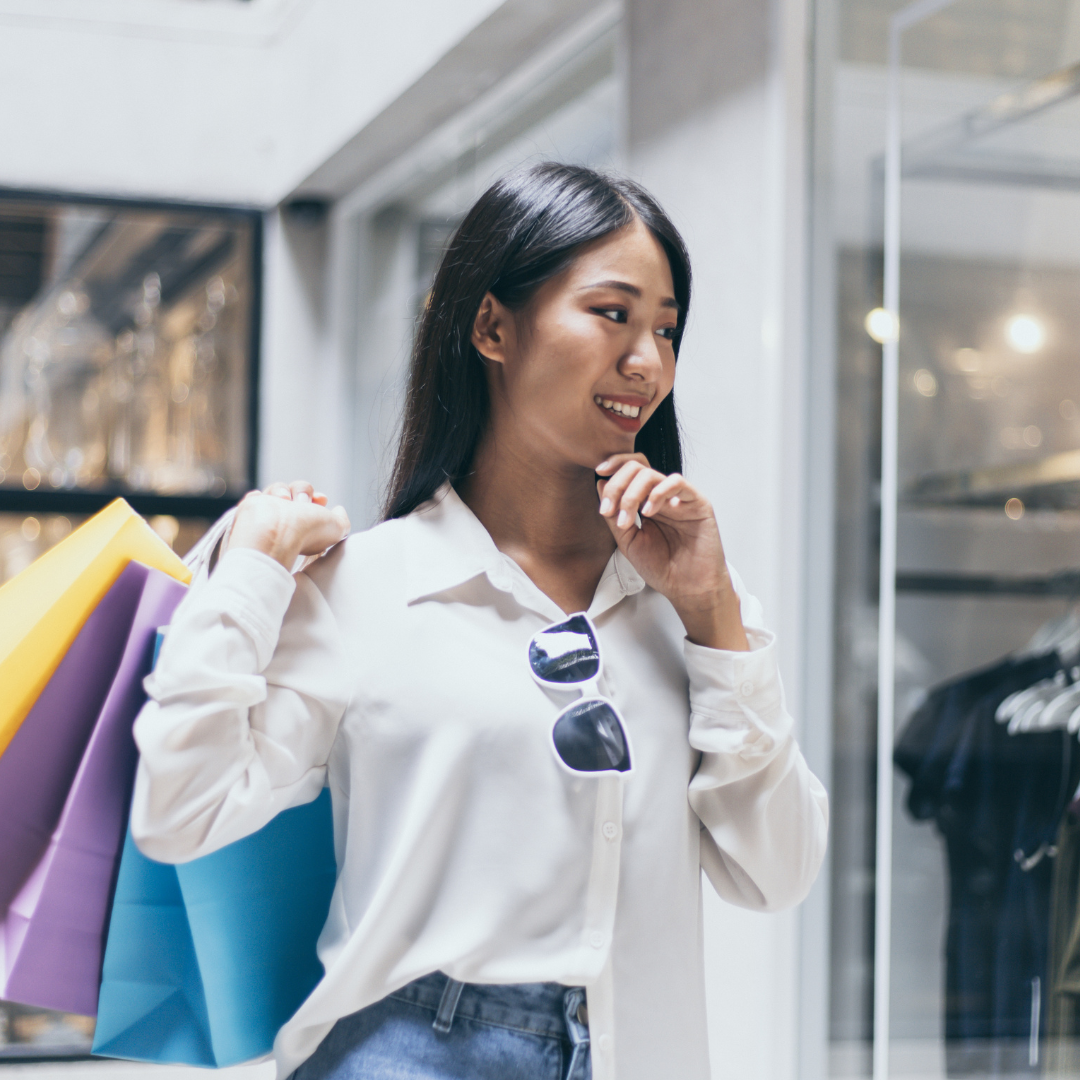 Woman shopping with colorful bags thinking of emotional spending triggers