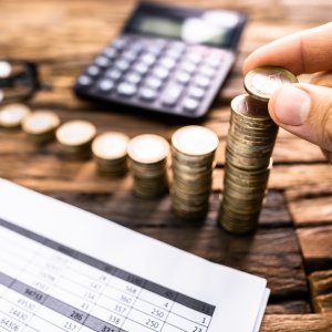 Coins stacked beside calculator and spreadsheet