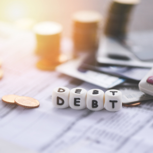 Dice spelling 'DEBT' on papers